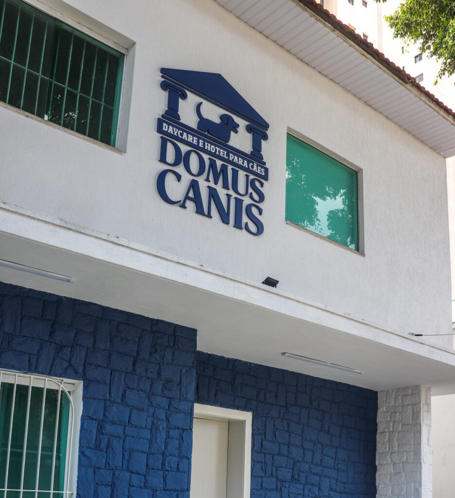 Fachada escola com logo Domus Canis, com a parte de cima branca e a parte de baixo azul.
