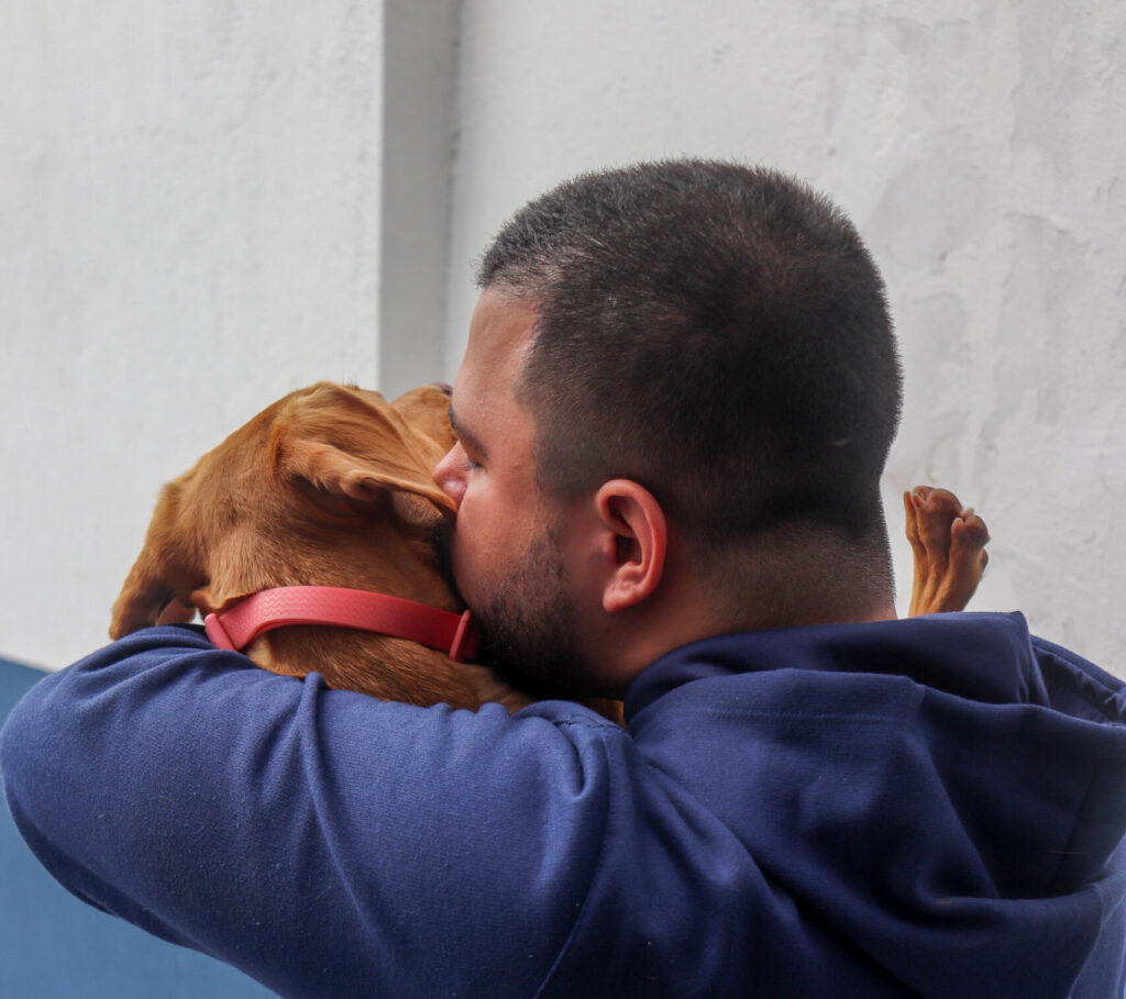 Homem de azul com cachorro caramelo no colo